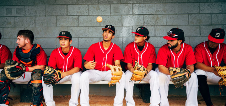 Confident young Hispanic baseball players sitting in dugout