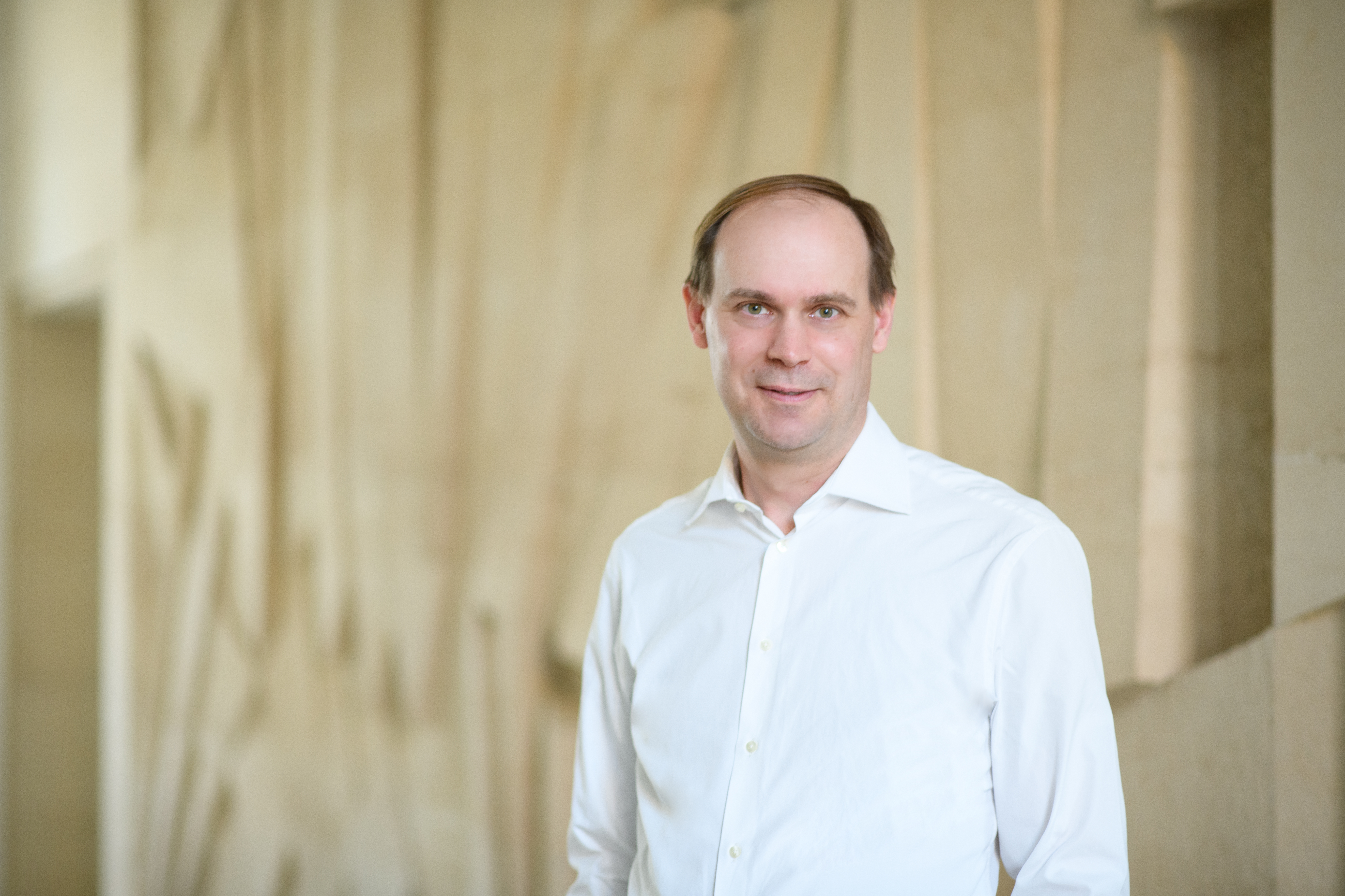 Portrait von Jannis Bischof. Er trägt ein weißes Hemd.