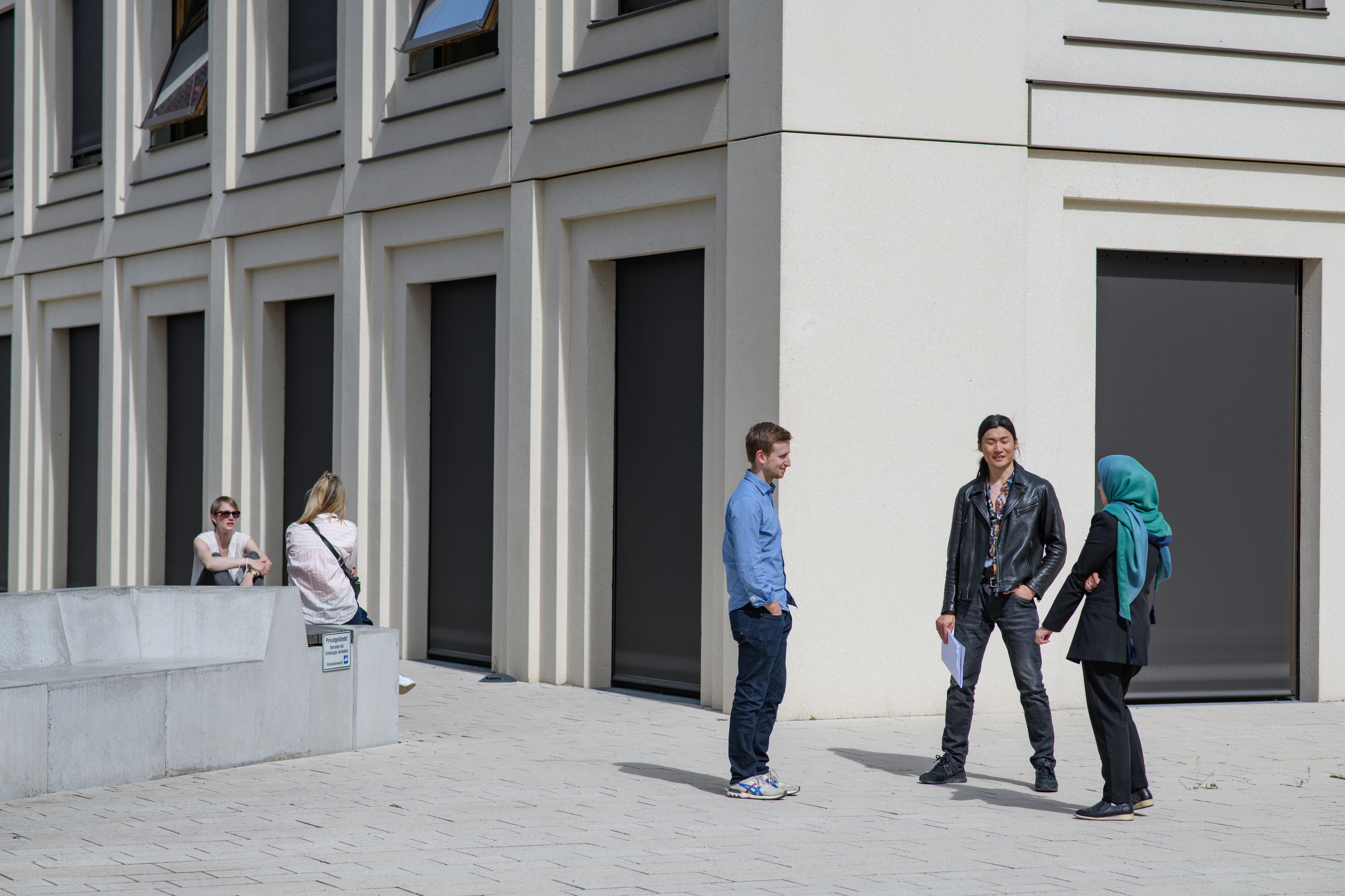 Ein paar Studierende unterhalten sich vor einem Universitätsgebäude