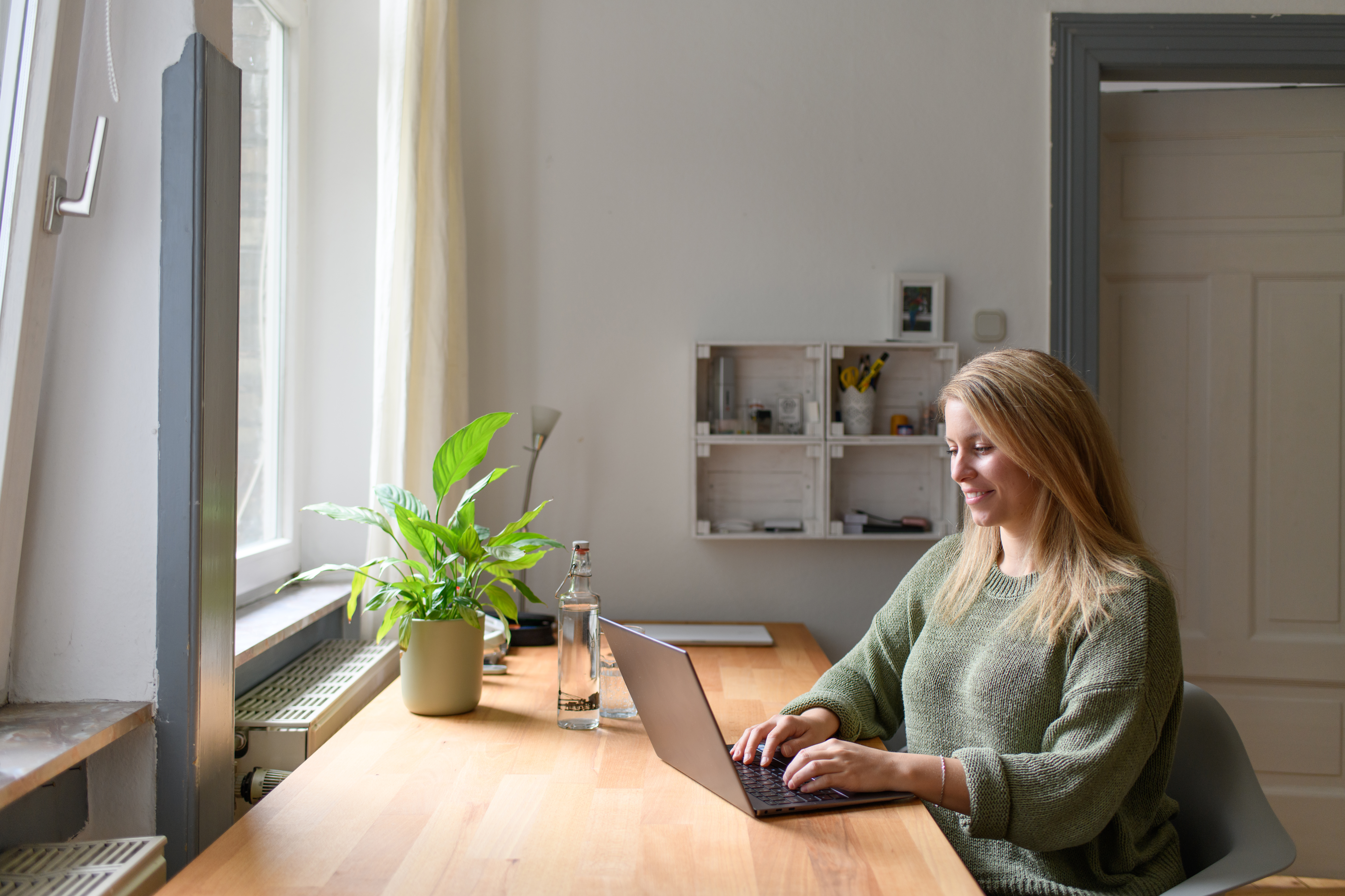 Studierende sitzt am Tisch und arbeitet am Laptop