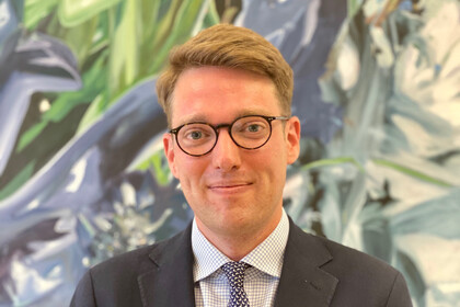 Prof. Vetter has short blond hair and wears glasses. He wears a suit and tie.