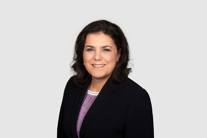 Prof. Aprea has shoulder-length dark hair and wears a dark blazer and a purple blouse.