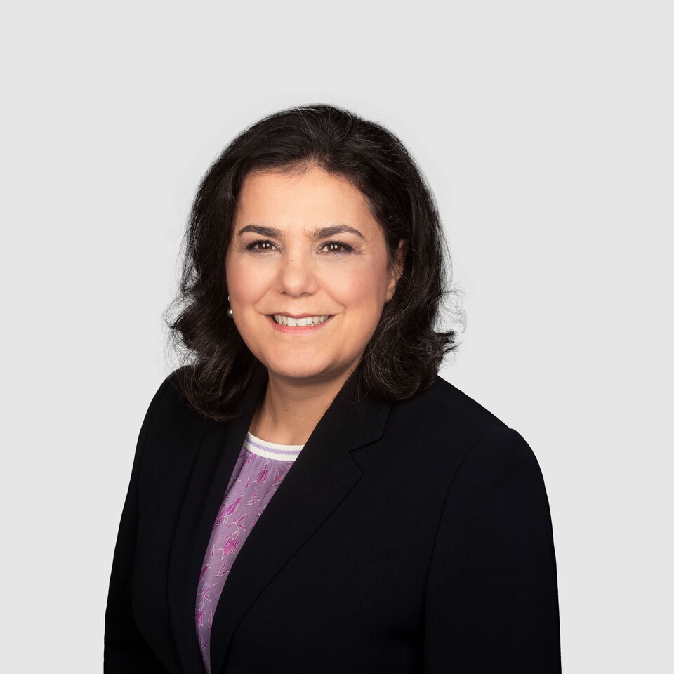 Prof. Aprea has shoulder-length dark hair and wears a dark blazer and a purple blouse.