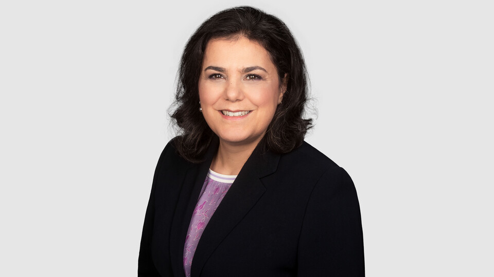 Prof. Aprea has shoulder-length dark hair and wears a dark blazer and a purple blouse.