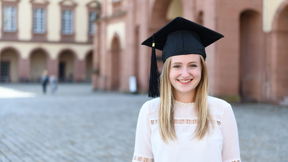 Bachelorabsolventin steht auf dem Ehrenhof vor dem Mannheimer Schloss.