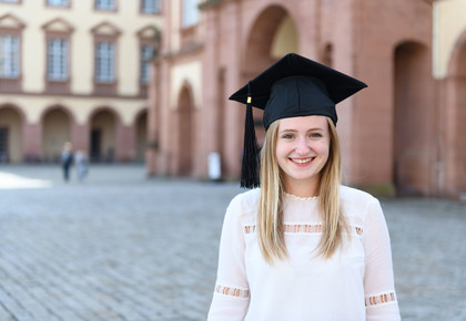 Bachelorabsolventin steht auf dem Ehrenhof vor dem Mannheimer Schloss.