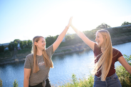 Studentinnen am Neckar Zwei Studentinnen stehen am Neckarkanal und klatschen sich mit High-Five ab. Sie lachen und sind fröhlich.