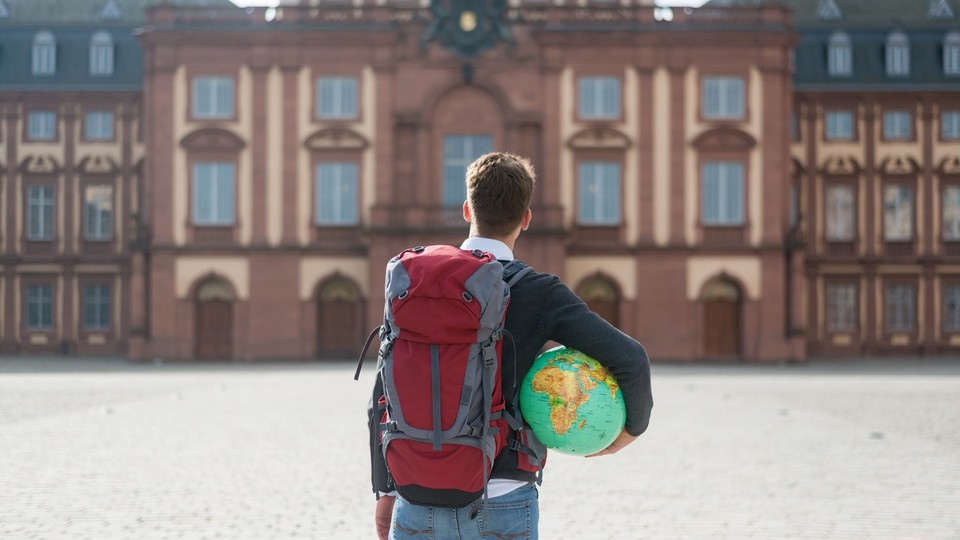Student mit Weltkugel unterm Arm vorm Schloss