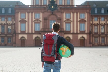 Student mit Weltkugel unterm Arm vorm Schloss