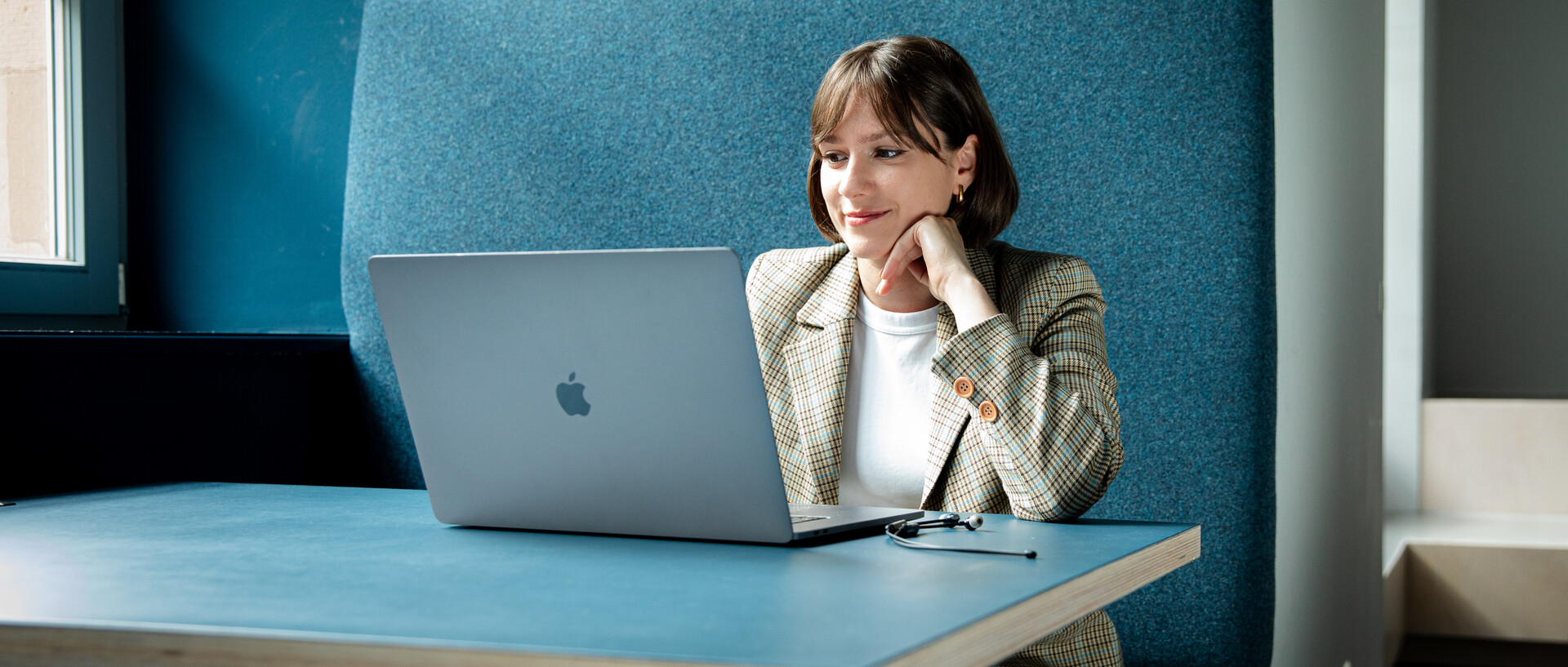 Eine Forscherin mit kurzen braunen Haaren arbeitet im Experience Lab an ihrem Laptop.