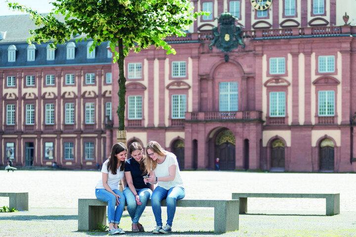 Studierende auf Bank vor dem Schloss