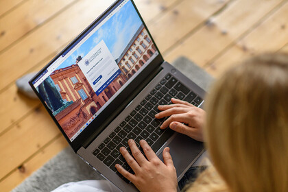 Eine Frau loggt sich auf ihrem Laptop bei einer Webseite ein.