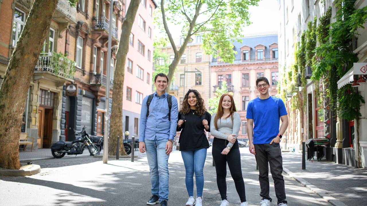 Four smiling students in a low-traffic zone in Mannheim’s Jungbusch district