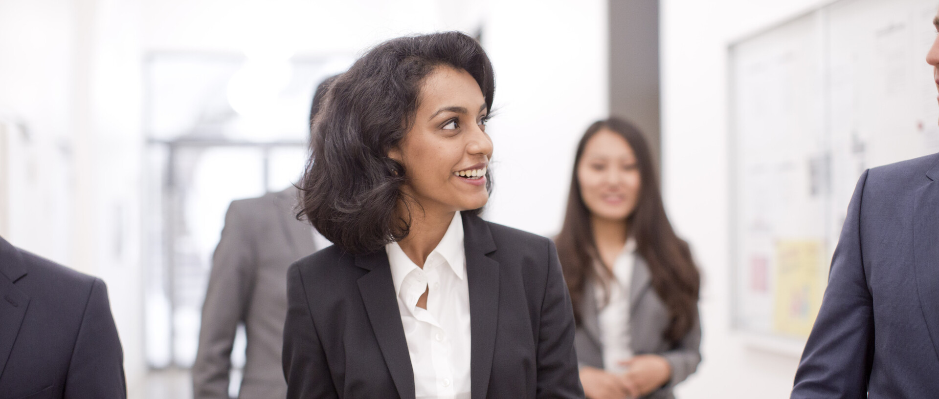 Personen in Business Kleidung laufen den Flur entlang