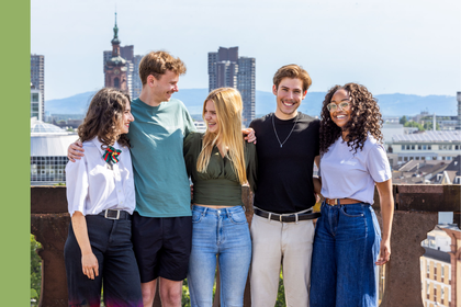 Fünf Studierende stehen auf dem Dach des Barockschlosses für ein Gruppenfoto. Im Hintergrund ist die Stadt Mannheim zu sehen.