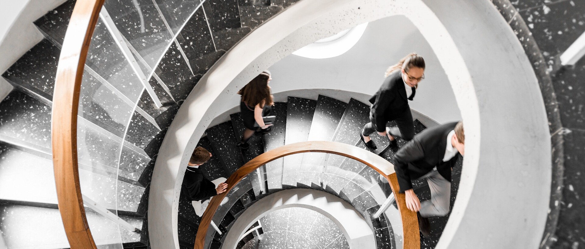 Vogelperspektive auf eine schwarze Wendeltreppe. Studierende gehen die Treppe hinauf. Link: Berufsperspektiven