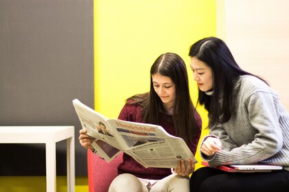 Zwei Studierende schauen in eine Zeitung