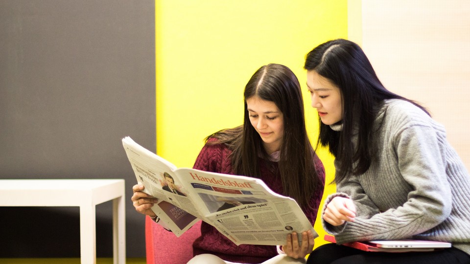 Zwei Studierende schauen in eine Zeitung