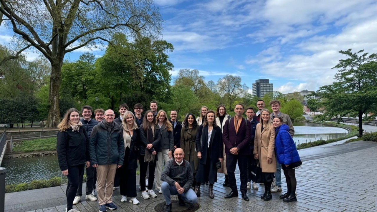 Gruppenfoto vor einem Bach mit Bäumen im Hintergrund