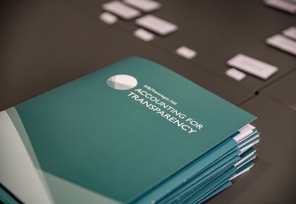 Türkisfarbene Mappen liegen auf einem schwarzen Tisch. Die Mappe haben die weiße Aufschrift "SFB/Transregio 266, Accounting for Transparency".