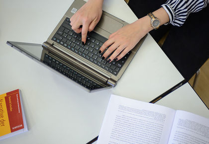 Zwei Hände einer Frau tippen auf einer Tastatur.