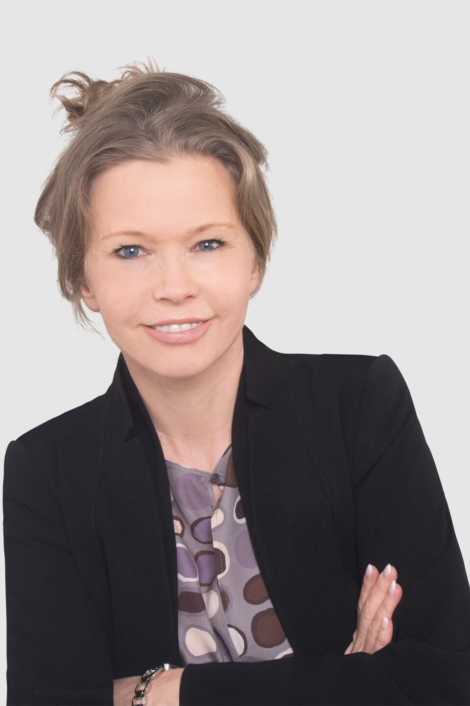 Prof. Schön trägt die Haare hochgesteckt und hat einen dunklen Blazer und eine gemusterte Bluse an.