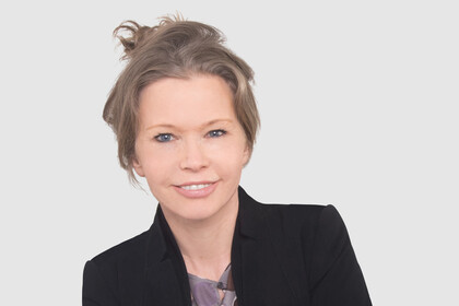 Prof. Schön trägt die Haare hochgesteckt und hat einen dunklen Blazer und eine gemusterte Bluse an.