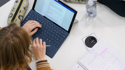 Eine Studentin sitzt an ihrem Laptop und lernt.