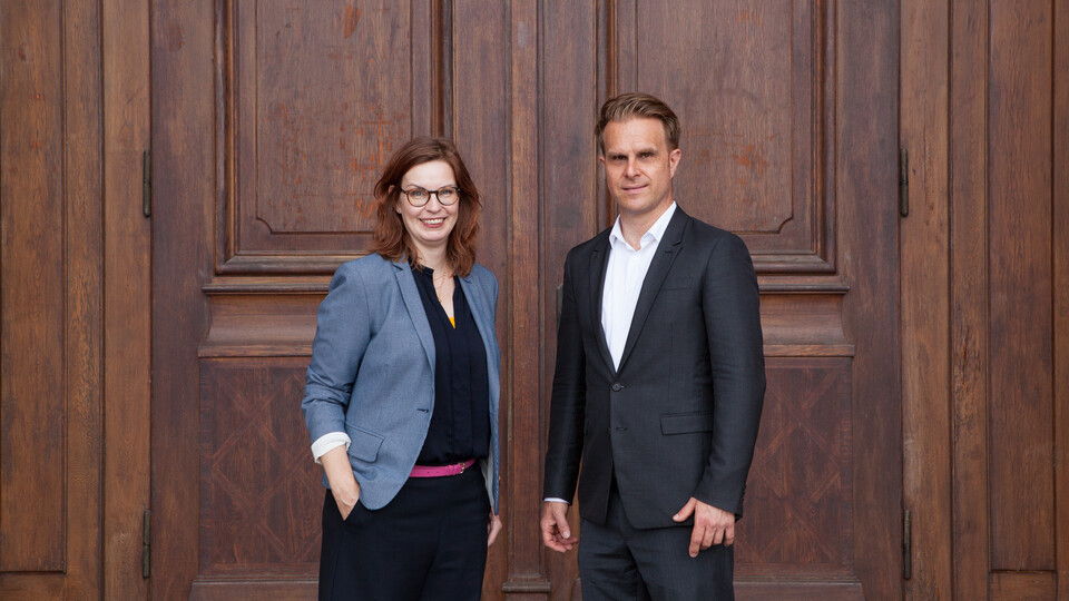 Florian Stahl und Sabine Gehrlein stehen vor einer großen Holztür.
