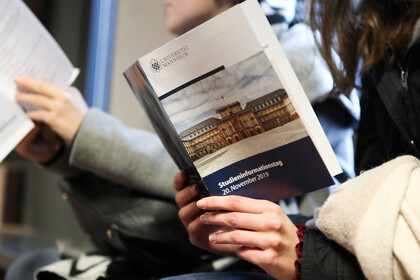 Zwei Studierende sitzen beisammen und lesen eine Broschüre zum Studieninformationstag.