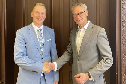 Two people shake hands in front of a door