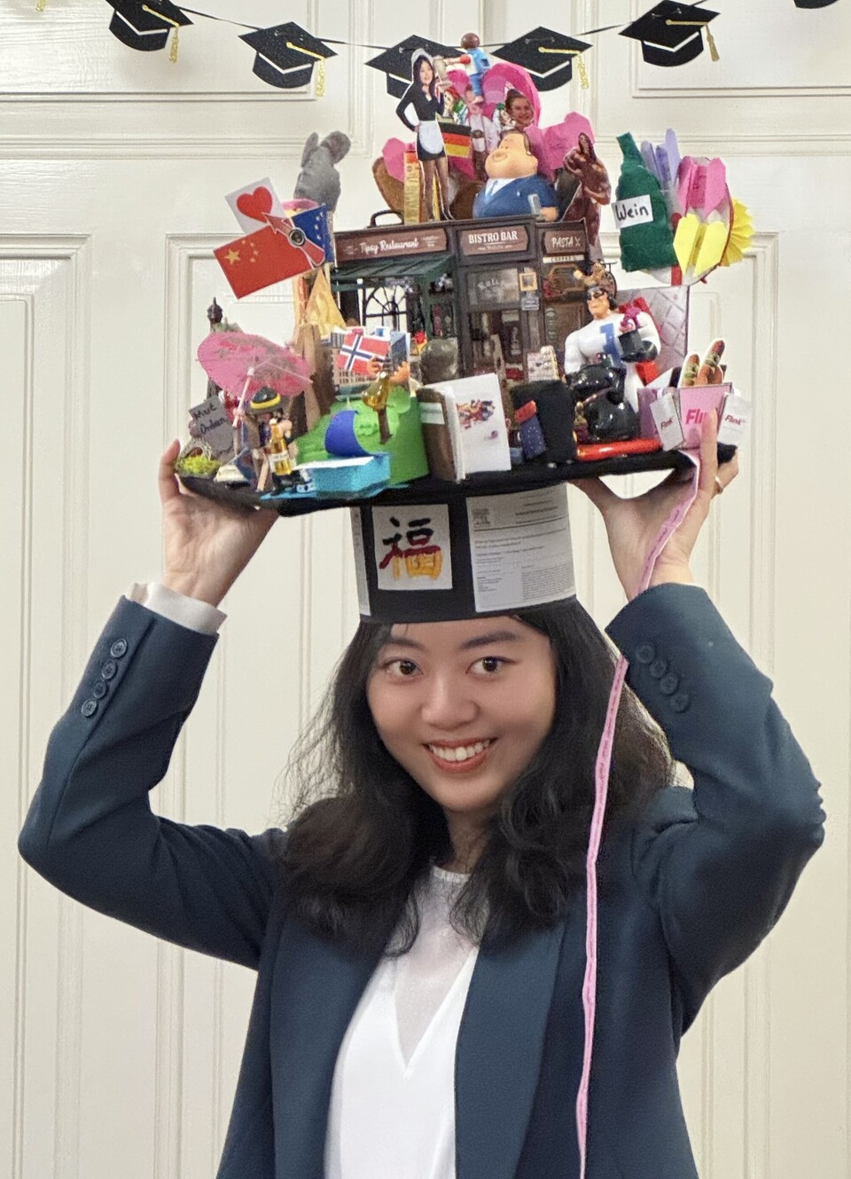 Porträt von Guzi Huang mit einem Doktorhut auf dem Kopf