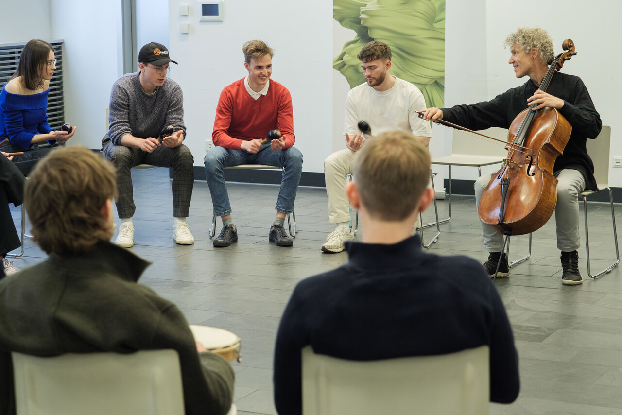 Group of people in a circle during a workshop led by a musician