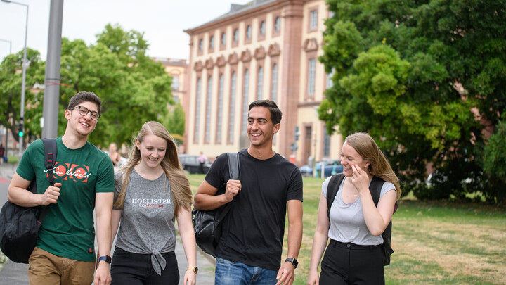 Eine Gruppe lachender Studierender. Im Hintergrund das Mannheimer Schloss.