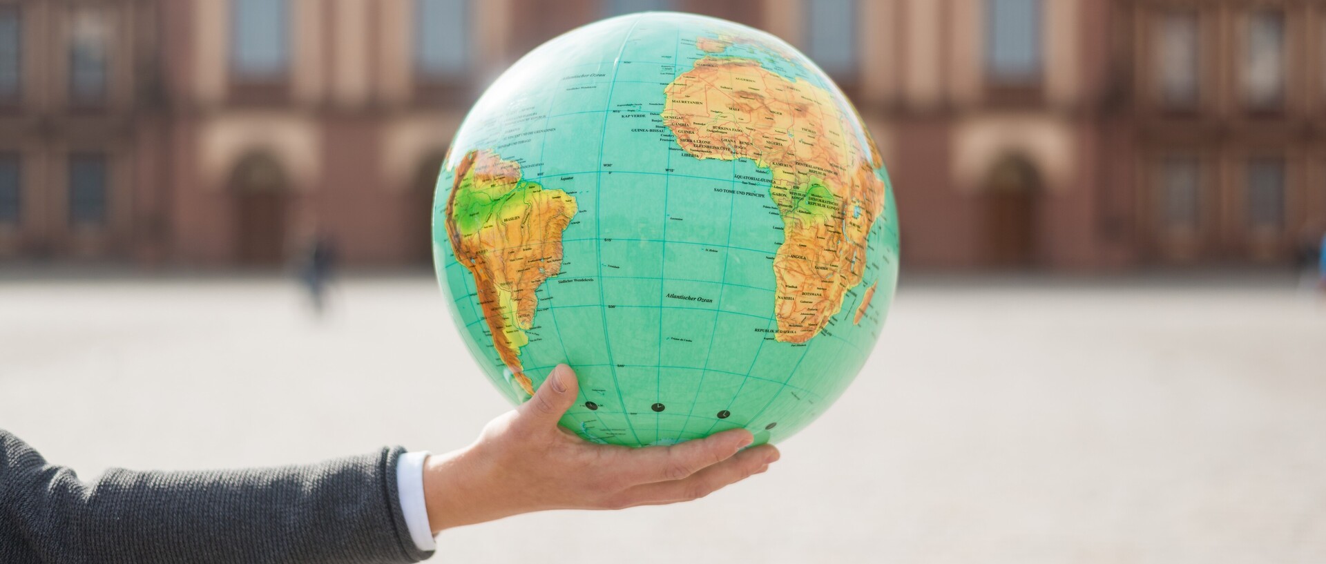 Hand holding a globe in front of the castle