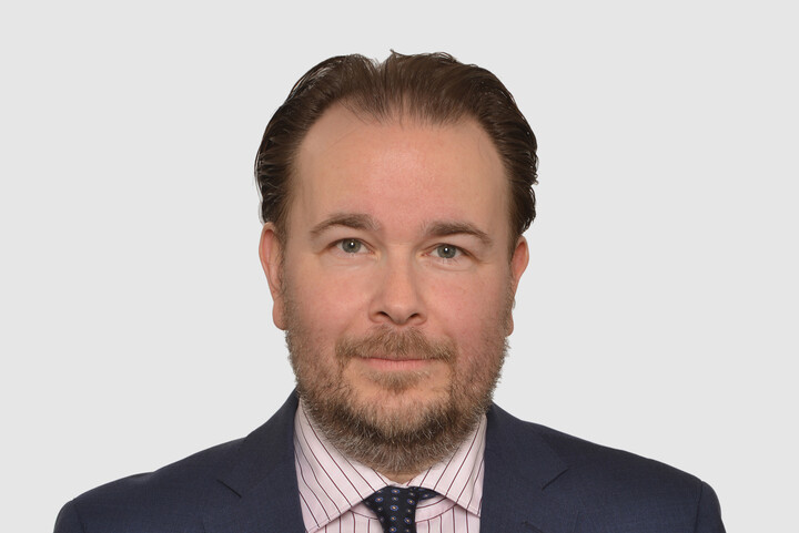 Prof. Danke hat kurze Haare und trägt Bart. Er trägt ein dunkelblaues Jacket, ein helles Hemd und eine dunkle Krawatte.
