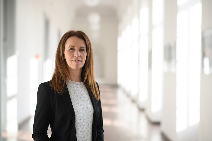 Prof. Niessen-Ruenzi hat lange, braune Haare und trägt ein schwarzes Jacket und eine weiße Bluse.