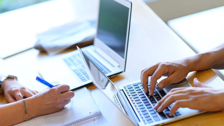 Ein Arbeitsplatz mit zwei Laptops, mit denen gearbeitet wird.