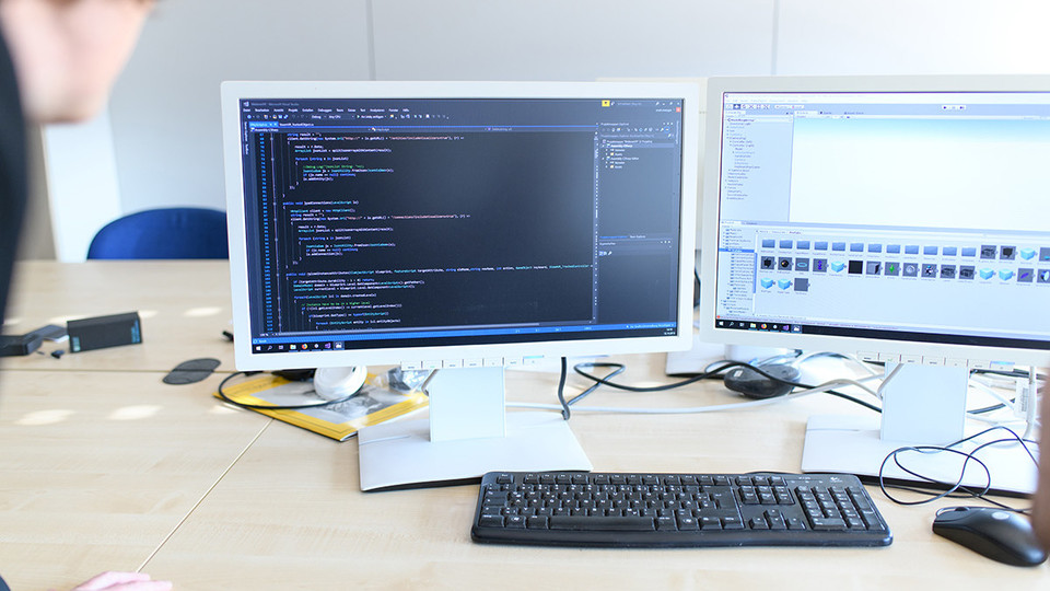 Arbeitsplatz, ein Tisch mit zwei Monitoren, auf welchen programmiert wird