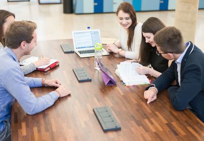 Studierende mit Lernmaterialien sitzen um Tisch
