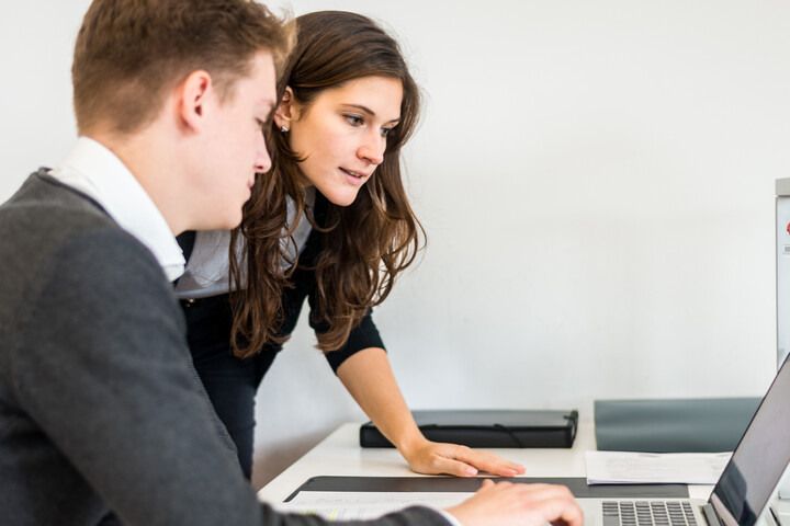 zwei Personen in Business Kleidung schauen auf einen Laptop