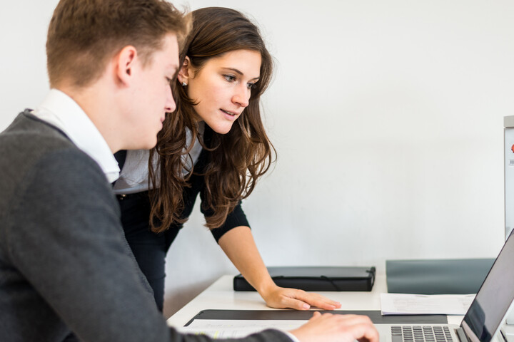 zwei Personen in Business Kleidung schauen auf einen Laptop