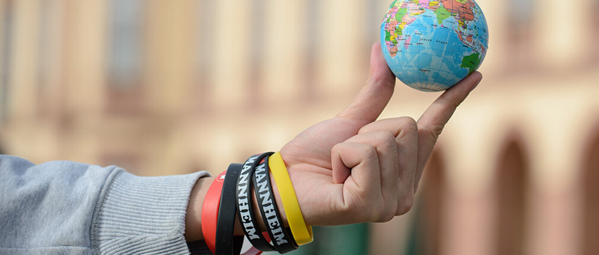 small globe is held between two fingers in front of the castle