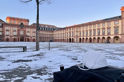 Maske auf Rucksack vor verschneitem Ehrenhof