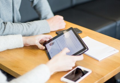 Hände, die Tablet halten am Tisch