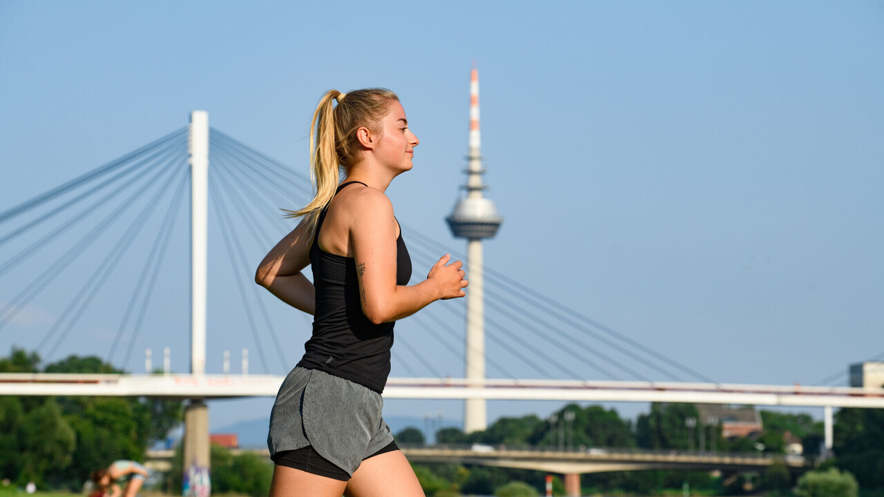 A runner at the Neckar shore. In the background, you can see the Collini-Steg and the Fernmeldeturm Mannheim.