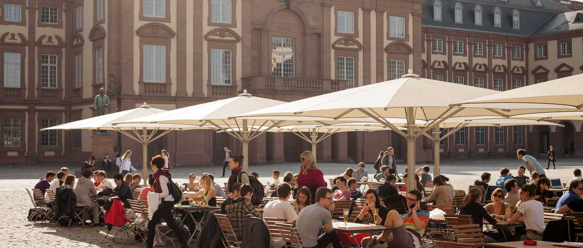 Café Ehrenhof Ost, Studierende sitzen draußen an Tischen auf dem Ehrenhof
