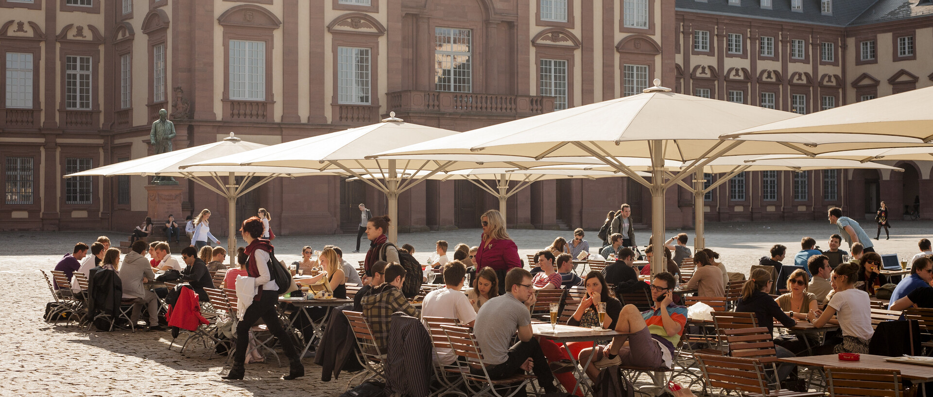 Café Ehrenhof Ost, Studierende sitzen draußen an Tischen auf dem Ehrenhof