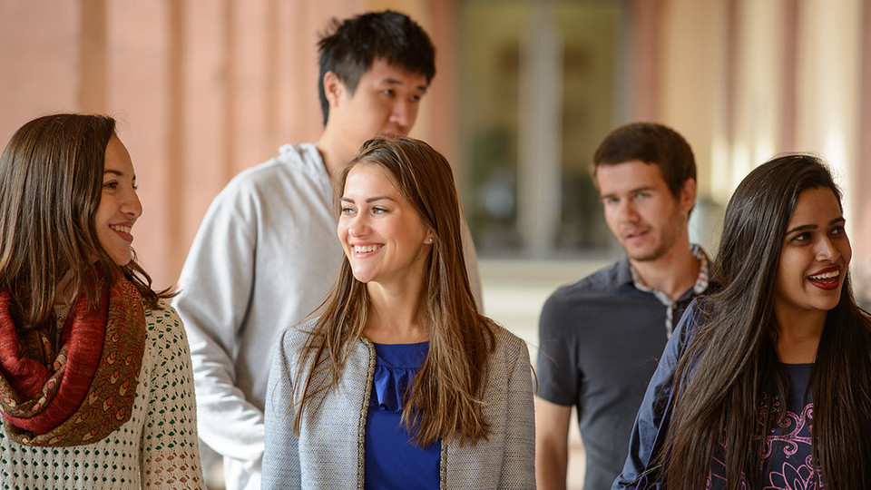 Fünf Studierende laufen über den Ehrenhof und unterhalten sich.