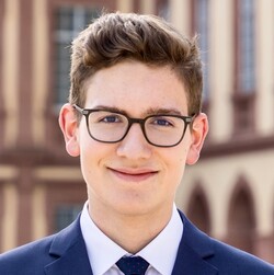 Christian Weber has short brown hair and wears a suit and black glasses